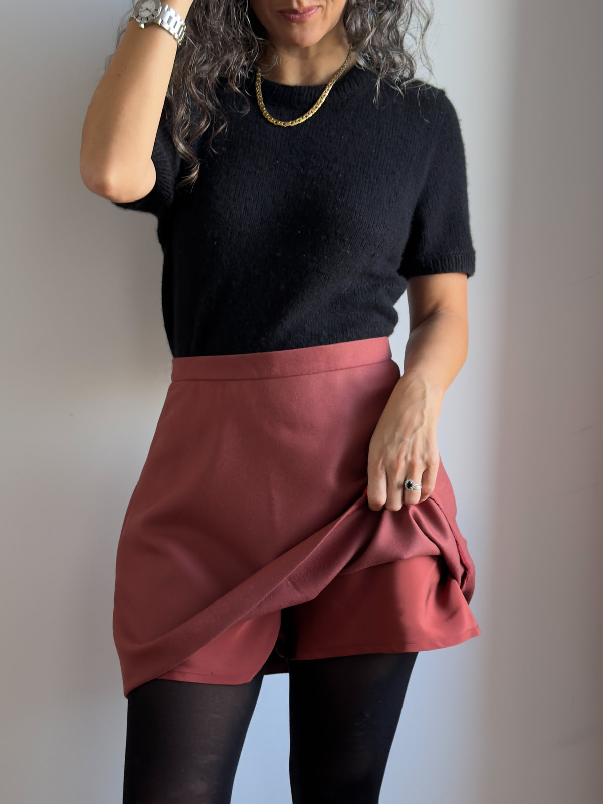 Karlie Skort sewing pattern, view A in the longer length, lifting the rust wool skirt to show the matching silk shorts